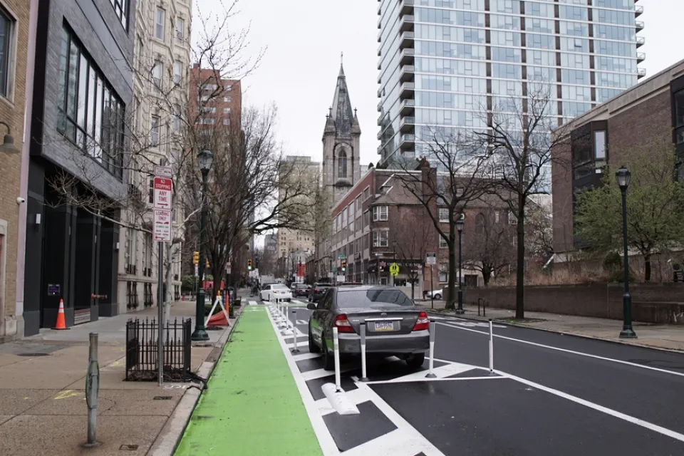 Green parking-protected bike lane in Philadelphia with old church in background